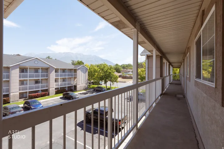 Exterior balcony with white railings, a painted concrete floor, and multiple windows