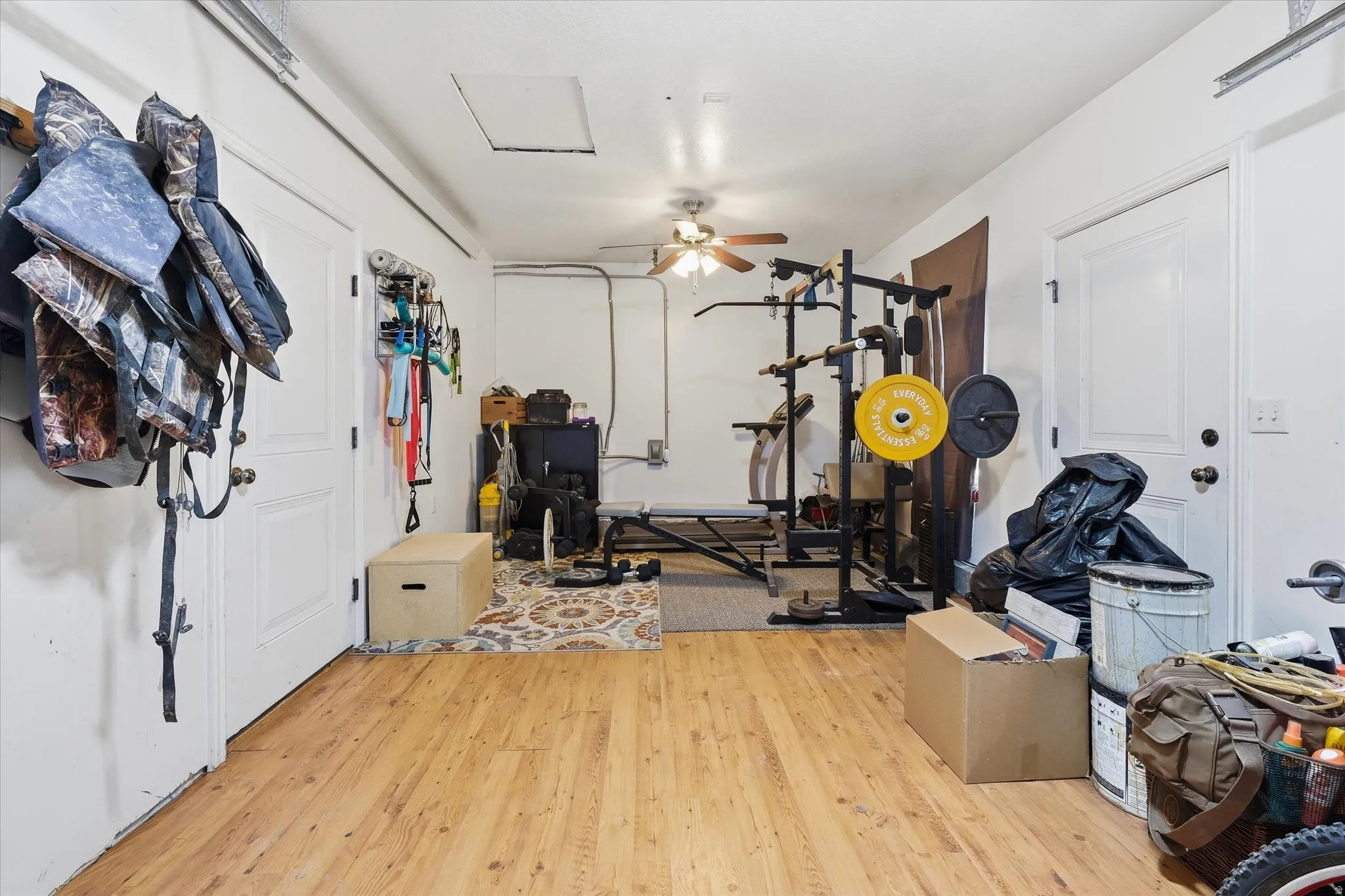 Versatile space featuring wood-finish flooring, white walls, and a ceiling fan