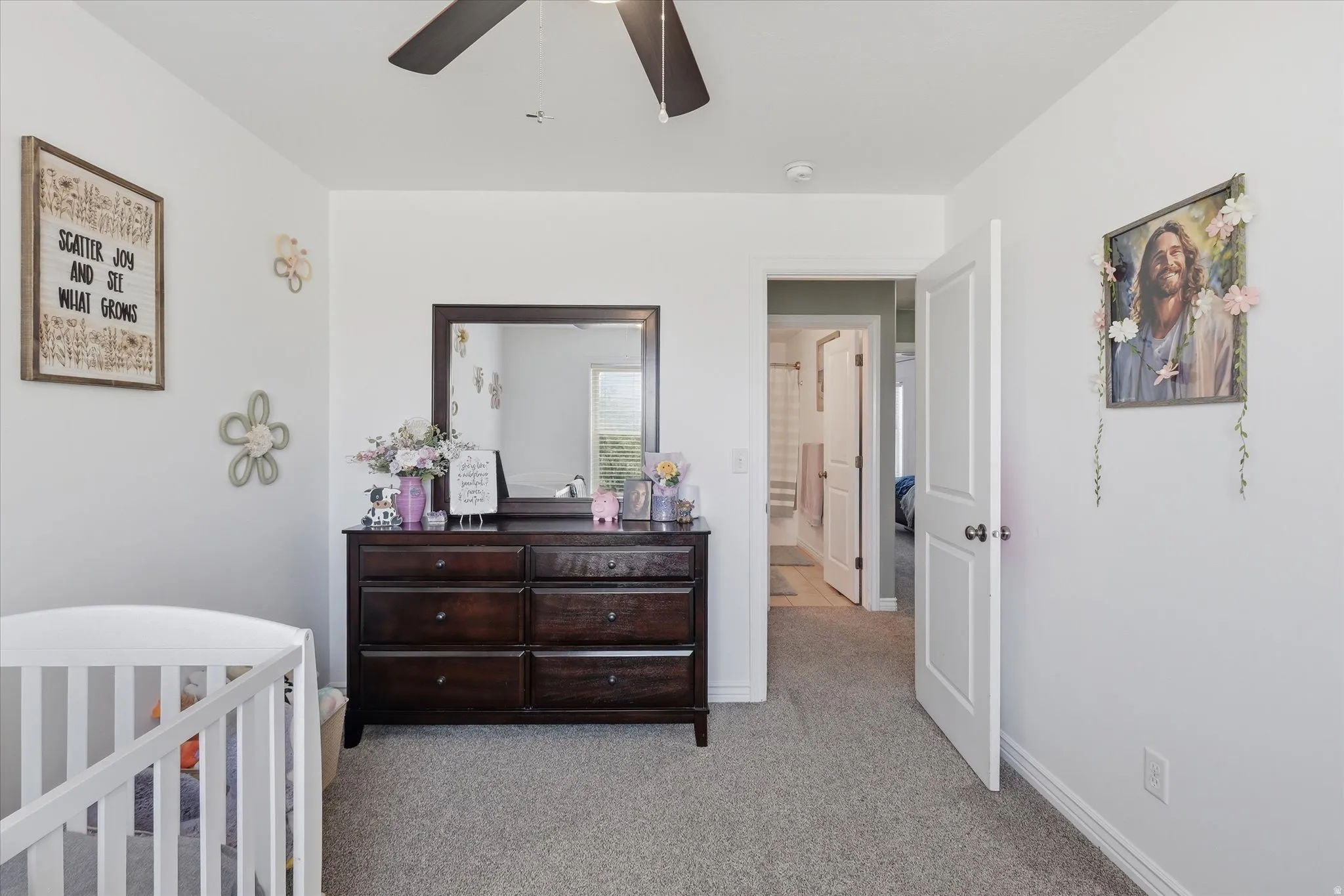 Bright room featuring light gray carpeting, a ceiling fan with integrated lighting, and a white interior door