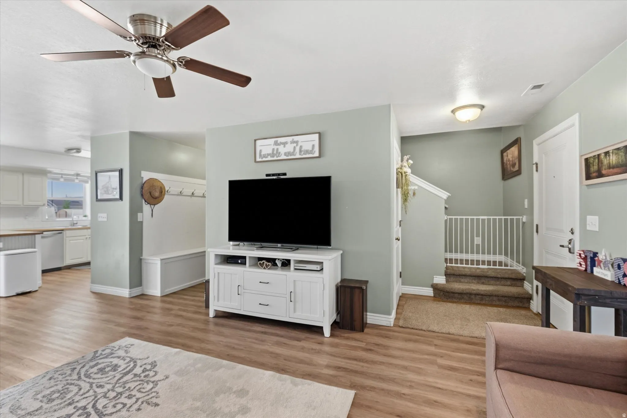 Open-concept living area featuring wood-finish flooring and a ceiling fan with integrated lighting