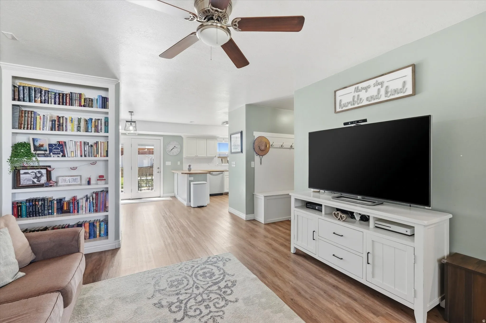 Spacious interior featuring wood-finish flooring, a ceiling fan, and built-in shelving