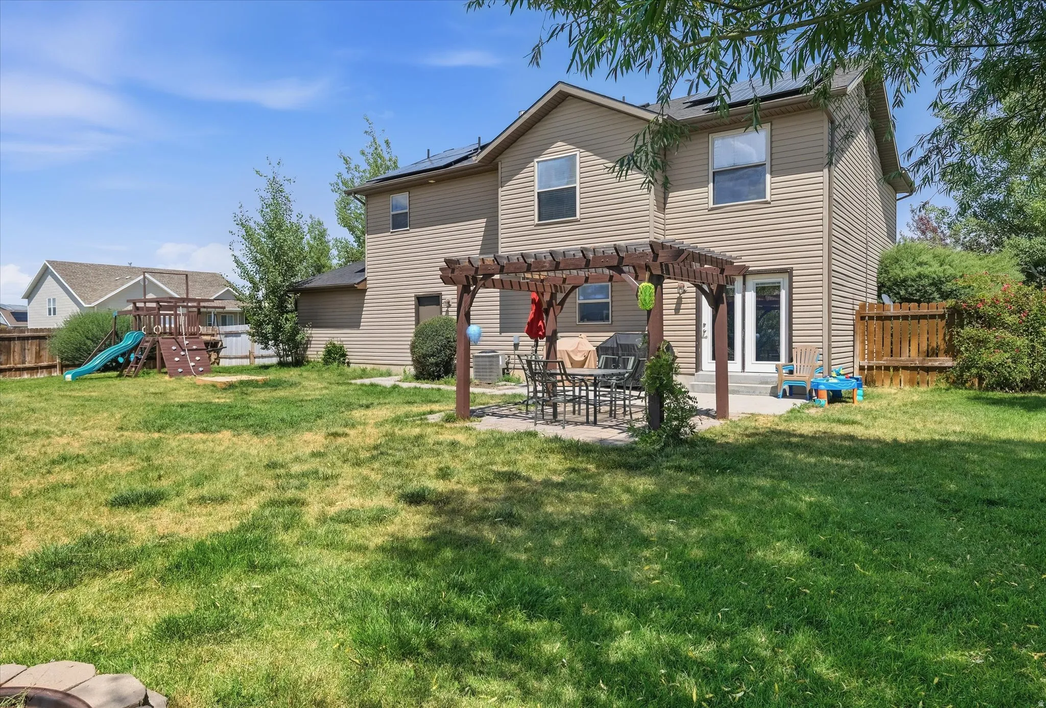 Spacious backyard with a pergola-covered patio, full vinyl siding, a privacy fence, and upper-level windows