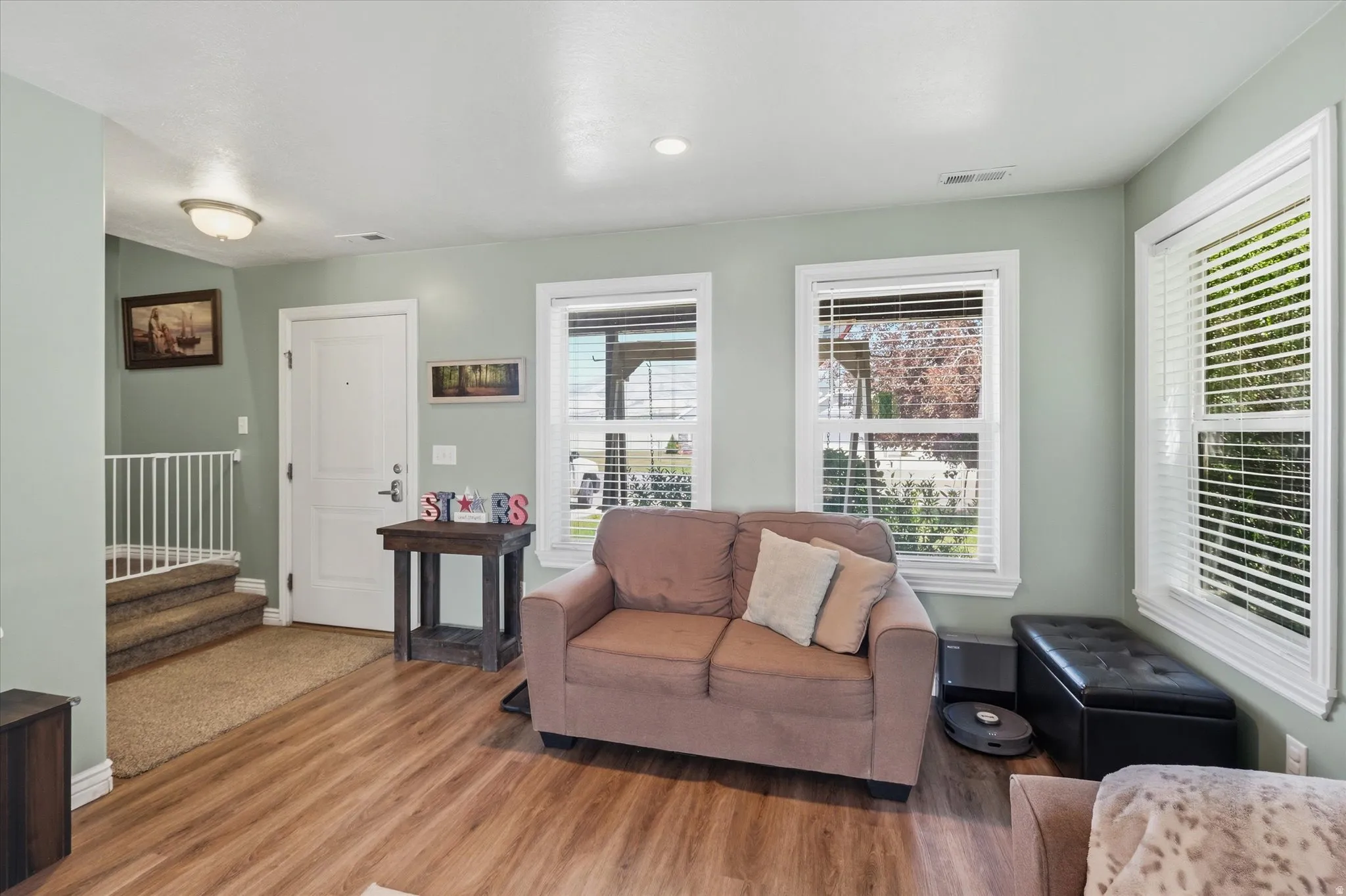 Spacious room with wood-finish flooring, light green walls, and white trim