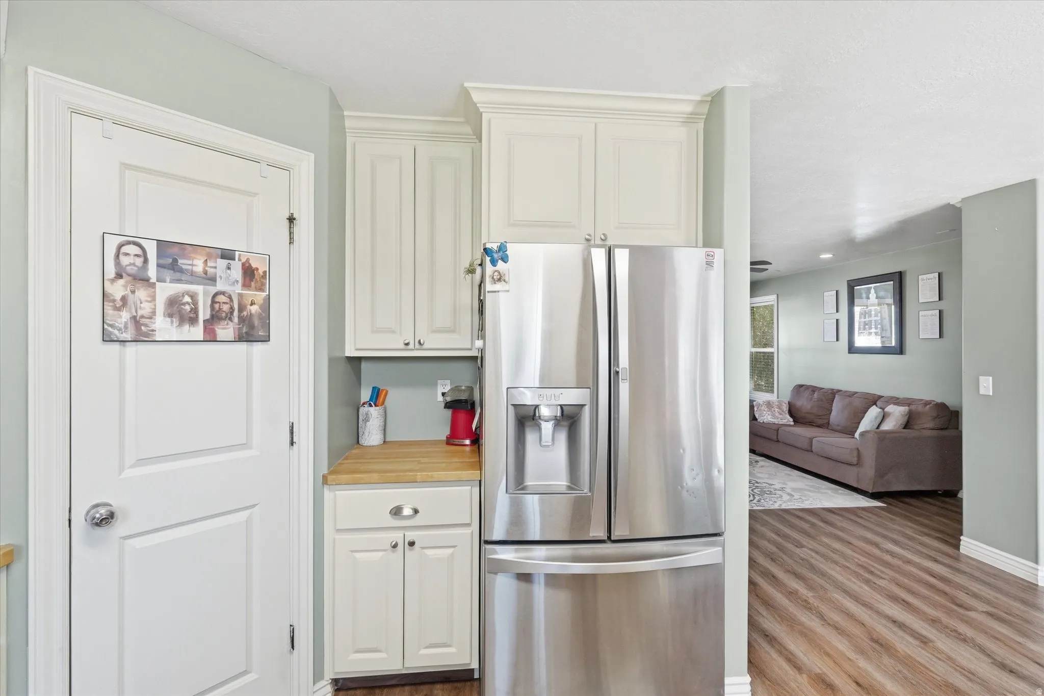 Stainless steel French door refrigerator set within custom cabinetry with crown molding, featuring a wood-finish countertop