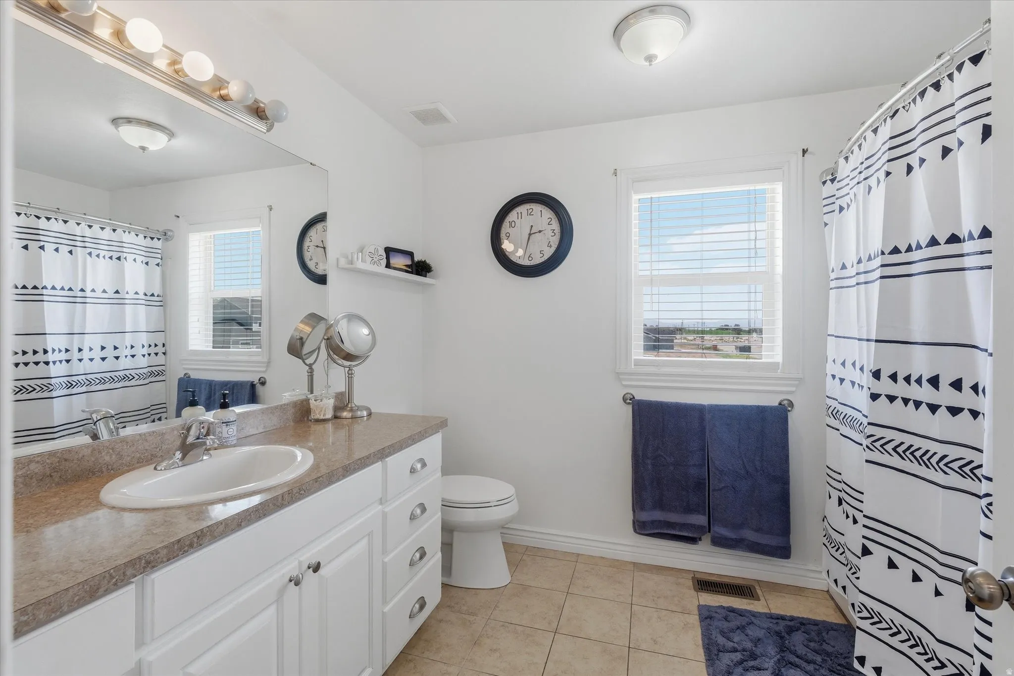 Bathroom featuring a single vanity with a laminate countertop, white cabinetry, and an integrated sink