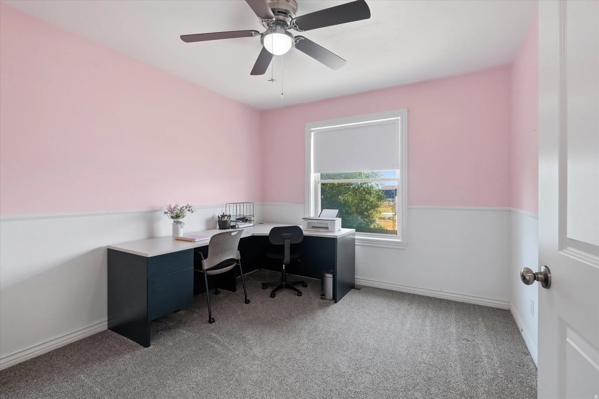 Bedroom featuring a ceiling fan with integrated lighting, a single window with a roller shade, and gray carpet flooring