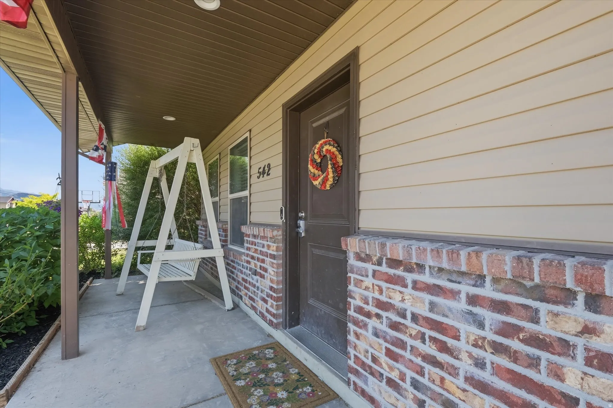 Covered porch entry featuring a concrete slab, brick accent wall, horizontal siding, and a recessed ceiling light