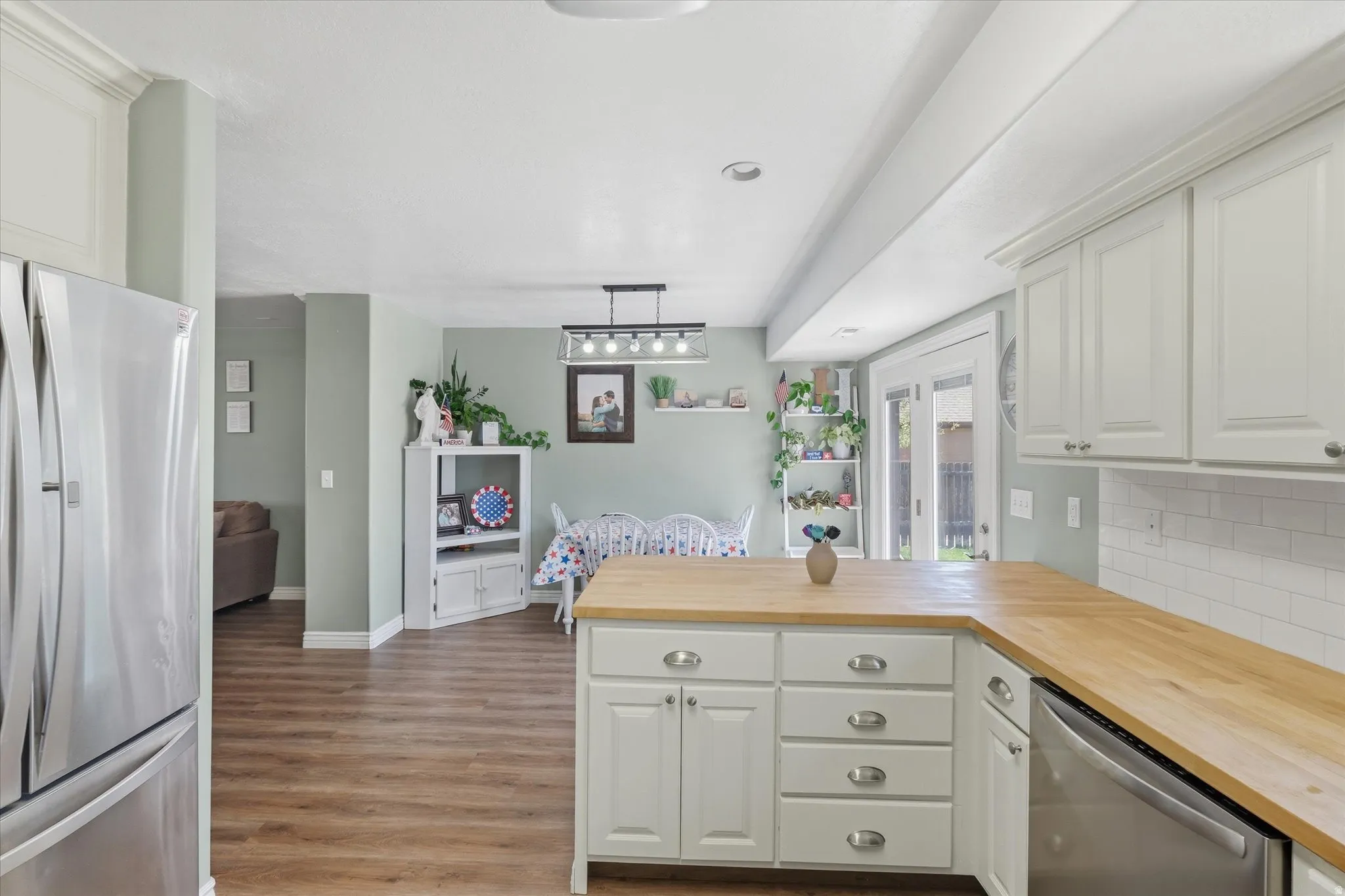 Kitchen featuring wood-finish flooring, white cabinetry, light wood countertops, and a subway tile backsplash