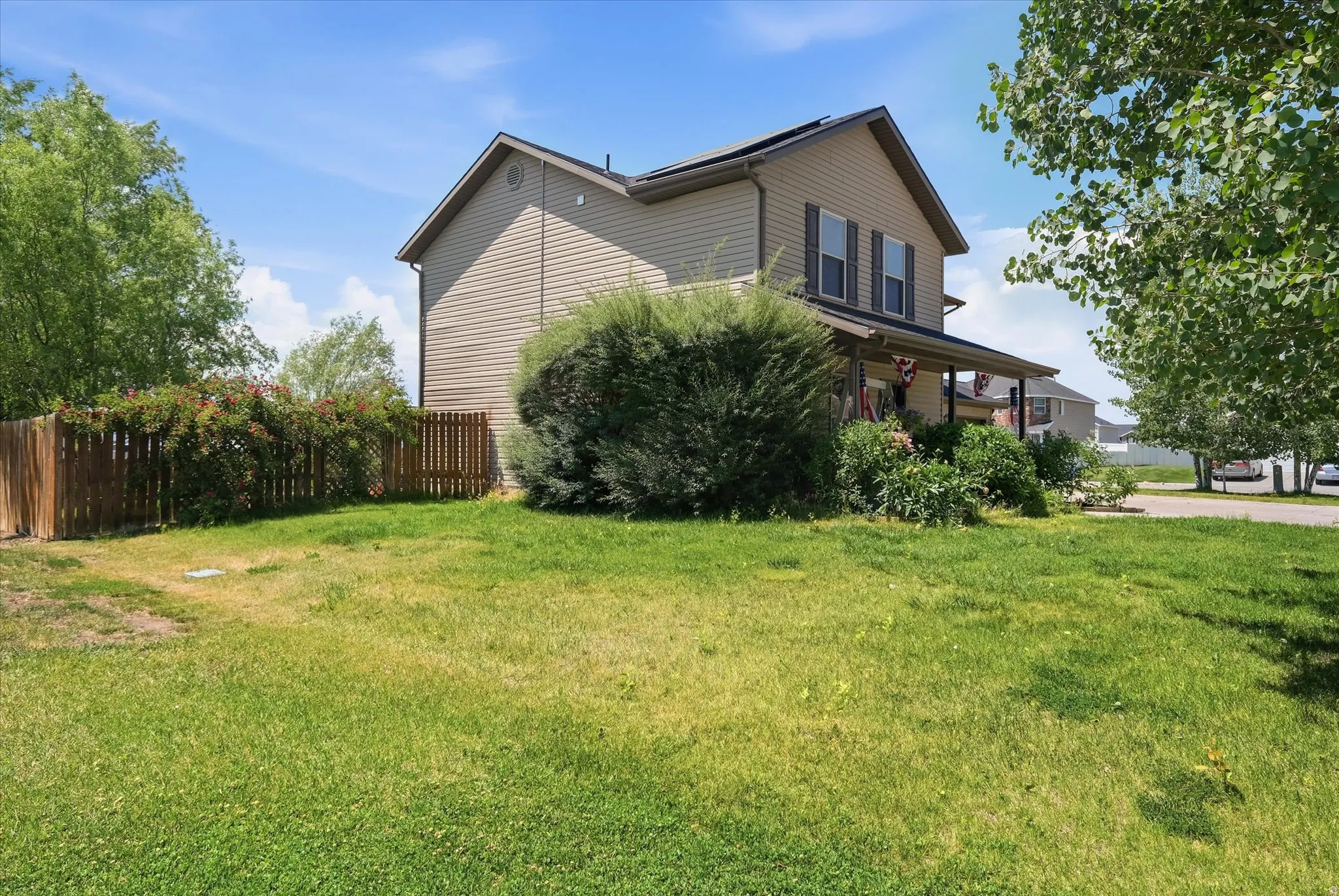 Two-story residence featuring light-colored siding, dark shutters, and a covered front porch
