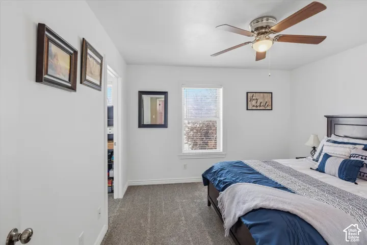 Bedroom featuring a window with blinds, a ceiling fan with integrated lighting, and carpet flooring