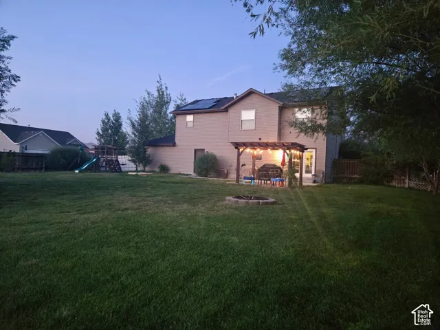 Expansive backyard featuring a manicured lawn, a fire pit, and a patio with a pergola