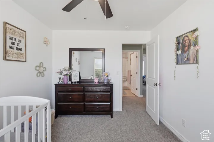 Bright room featuring light gray carpeting, a ceiling fan with integrated lighting, and a white interior door
