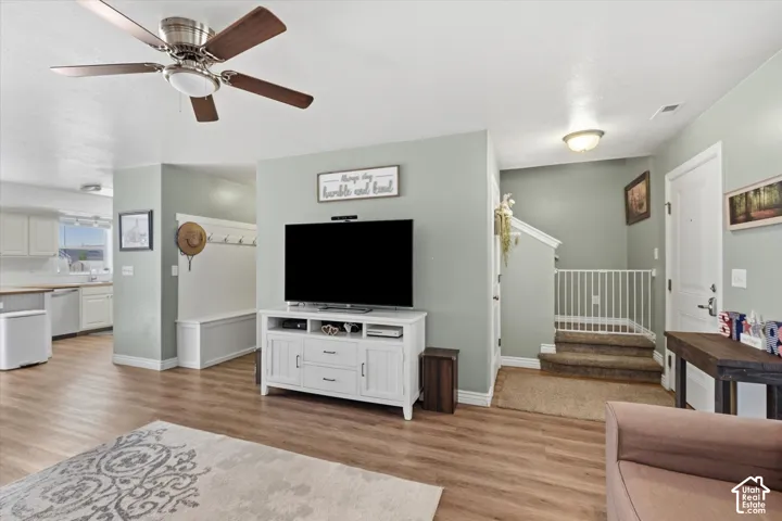 Open-concept living area featuring wood-finish flooring and a ceiling fan with integrated lighting