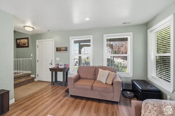 Spacious room with wood-finish flooring, light green walls, and white trim