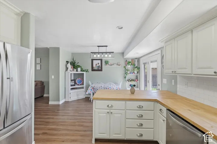 Kitchen featuring wood-finish flooring, white cabinetry, light wood countertops, and a subway tile backsplash