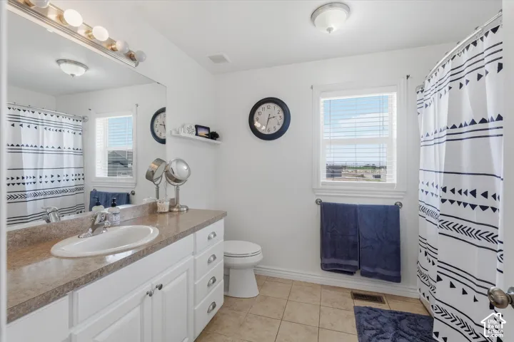 Bathroom featuring a single vanity with a laminate countertop, white cabinetry, and an integrated sink