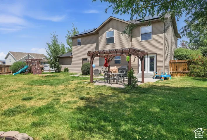 Spacious backyard with a pergola-covered patio, full vinyl siding, a privacy fence, and upper-level windows