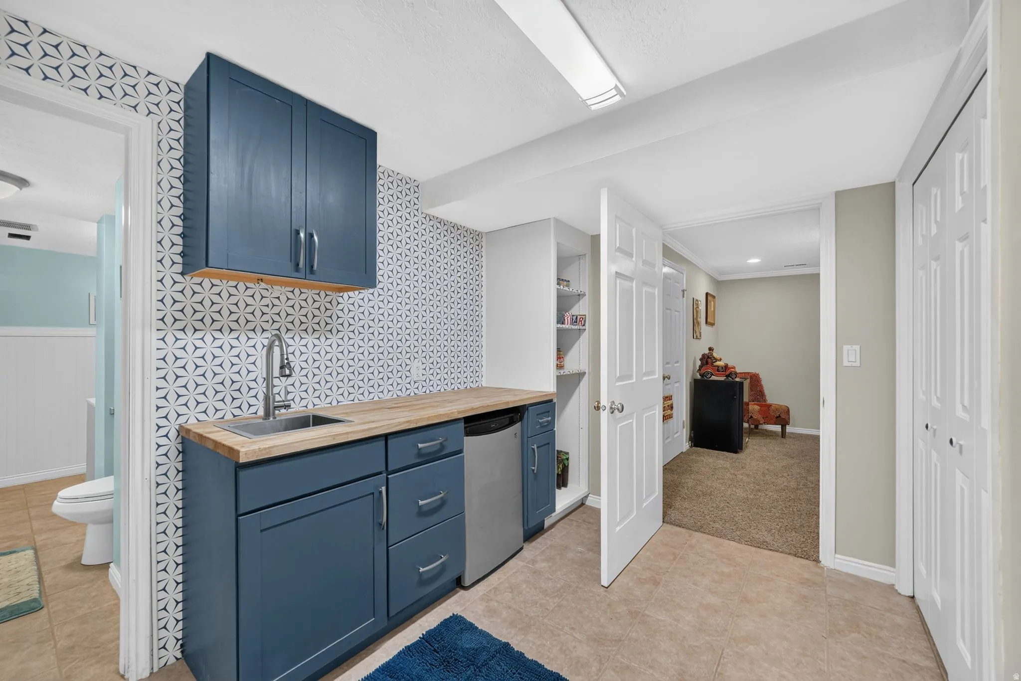 Compact kitchenette featuring blue cabinetry, wood-finish countertop, and a stainless steel sink