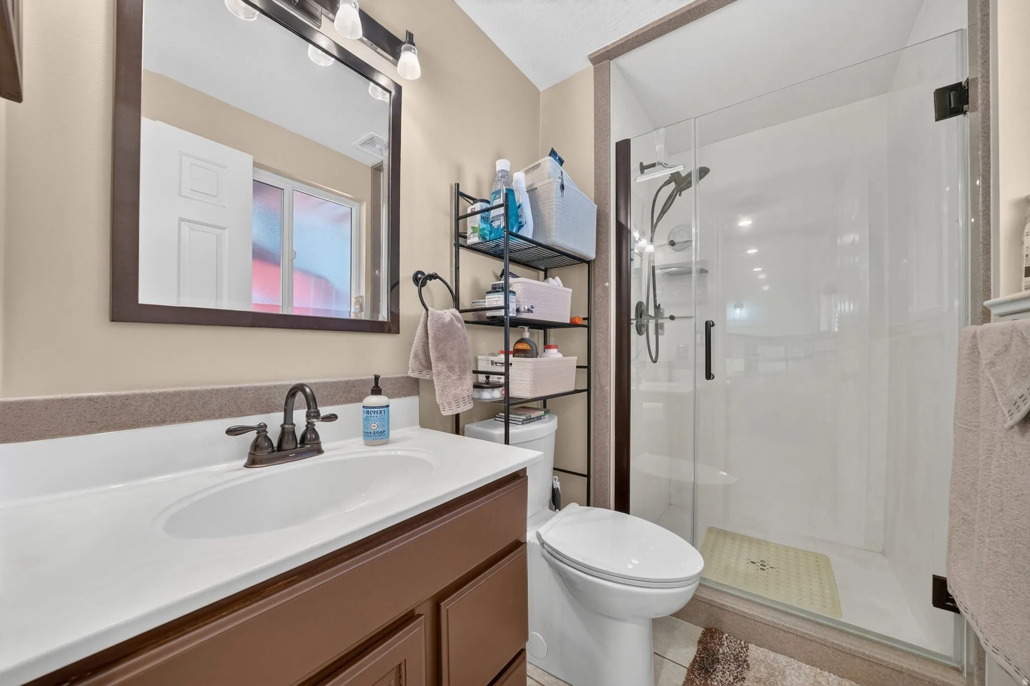 Bathroom featuring a vanity with a white integrated sink, bronze-finish faucet, and a large framed mirror