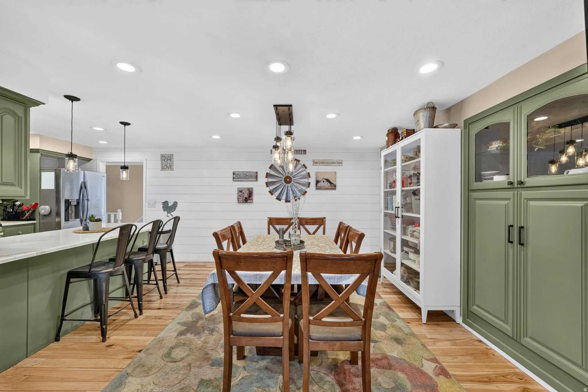 Open-concept kitchen and dining area featuring wood-finish flooring, recessed lighting, and a shiplap accent wall