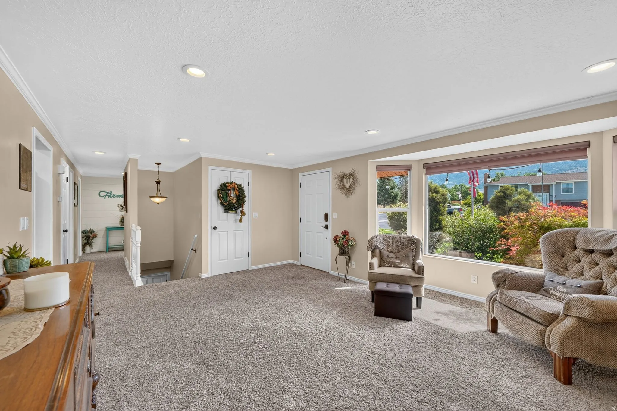 Spacious living area featuring neutral carpet flooring, recessed lighting, and a prominent bay window