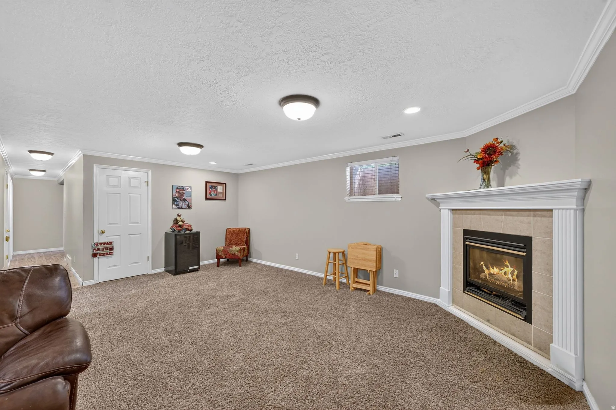 Living area featuring a corner fireplace with tile surround and white mantel, recessed lighting, and crown molding