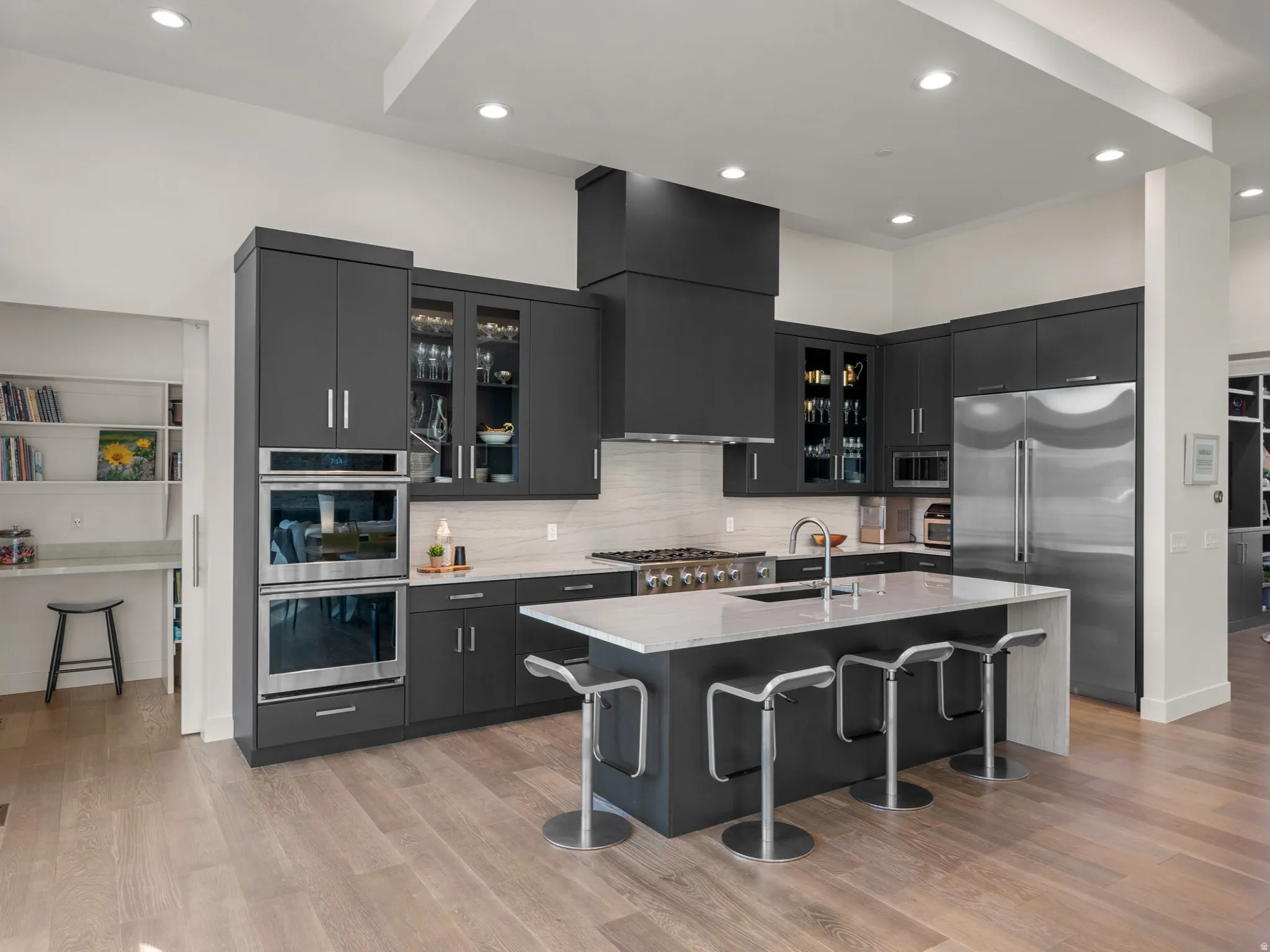 Contemporary kitchen featuring dark cabinetry, stainless steel appliances, and a central island with countertop seating