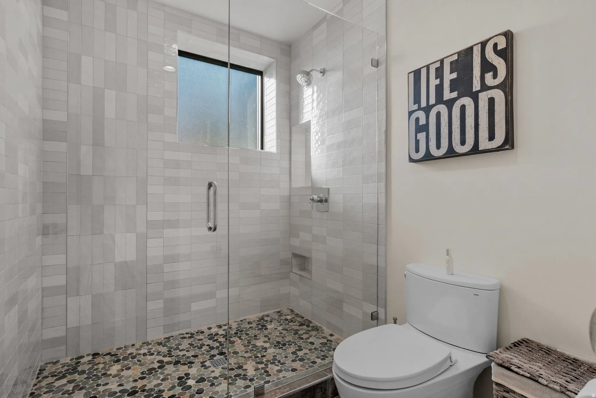 Walk-in shower with euro glass enclosure and pebble-tiled floor