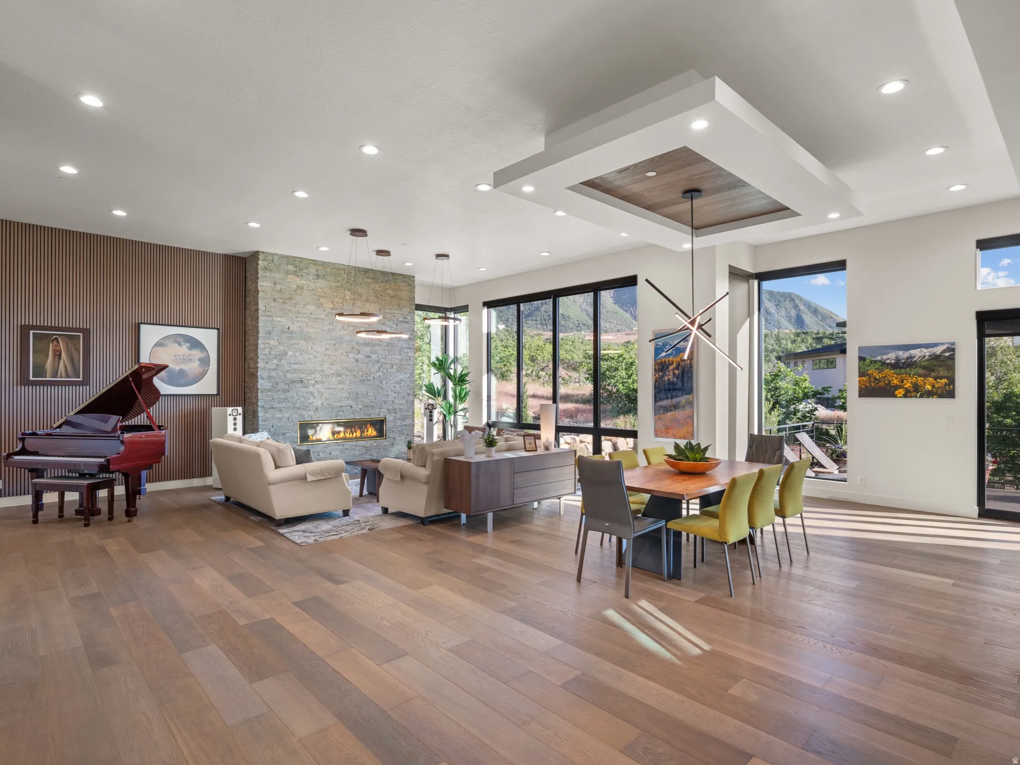 Spacious open-concept great room with 12' ceilings, large windows, beautiful hardwood floors and a stone-clad fireplace