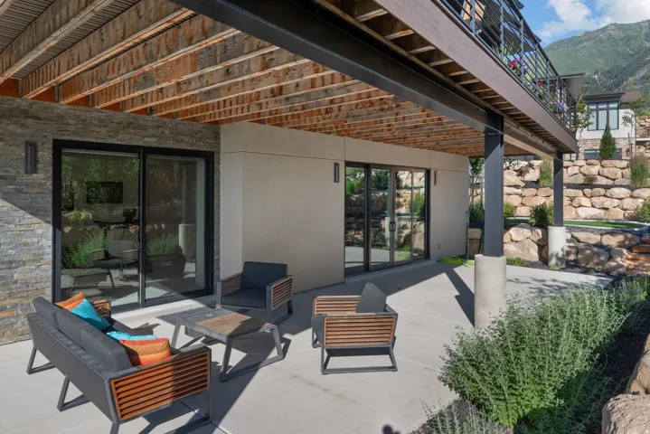 Expansive concrete patio beneath a wooden-beamed deck