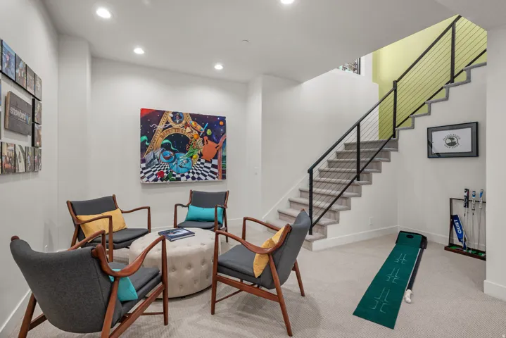 Open concept room featuring recessed lighting, a modern staircase with cable railing, and light-colored carpeting