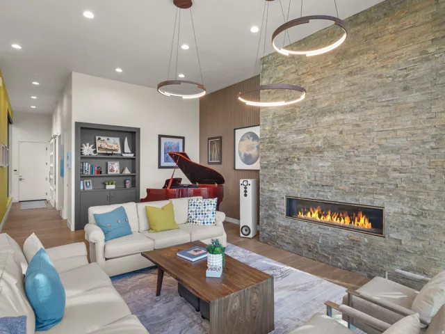 Living area featuring floor-to-ceiling stacked stone fireplace, hardwood flooring, recessed lighting, and contemporary pendant fixtures