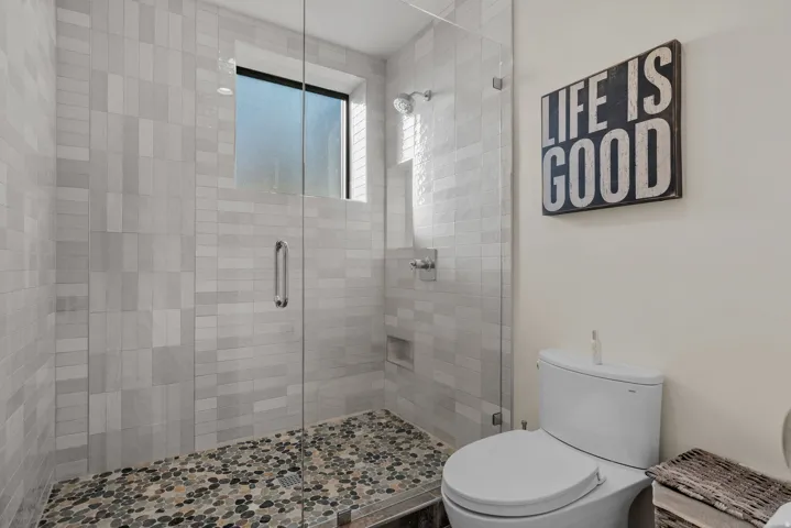 Walk-in shower with euro glass enclosure and pebble-tiled floor