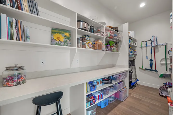 Spacious pantry featuring extensive open shelving, a built-in countertop workspace