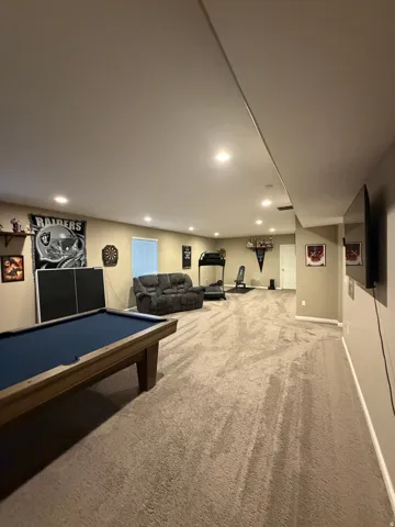 Spacious recreation room featuring recessed lighting, neutral wall paint, and plush carpeting throughout