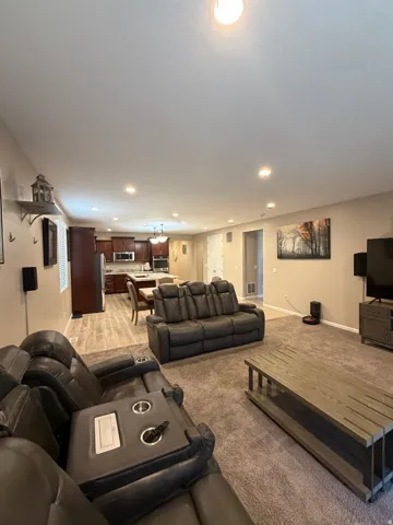 Open-concept living space featuring recessed lighting, a neutral color palette, wood-finish flooring, and dark wood cabinetry