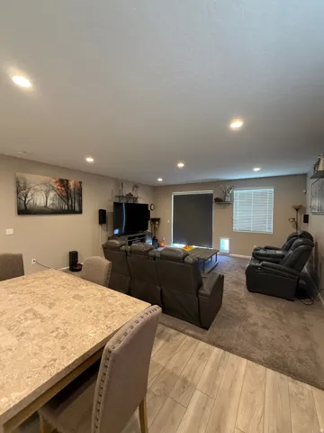 Open-concept living space featuring recessed lighting, a neutral color palette, wood-finish flooring, and a window with horizontal blinds