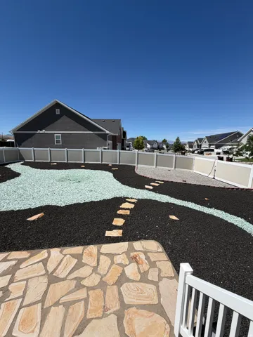 Hardscaped backyard featuring flagstone patio, pebble stone pathways, and decorative rock landscaping