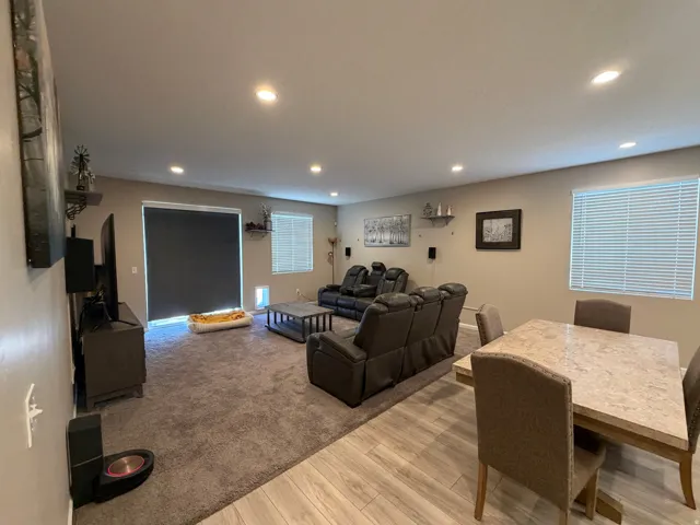 Open-concept living space featuring recessed lighting, a sliding glass door with a privacy shade, and two windows with blinds