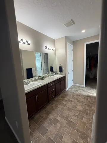 Dual vanity featuring white integrated sinks, dark wood cabinetry, and a light speckled countertop