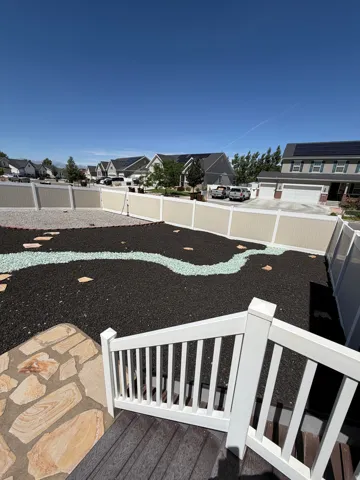 Expansive backyard featuring decorative black mulch, light-colored gravel, and a winding light-colored stone path
