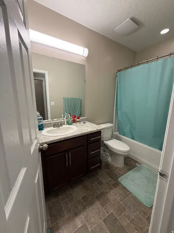 Bathroom featuring a dark wood vanity with a white countertop and integrated sink, a full-width mirror, a tub/shower combination, and tiled flooring