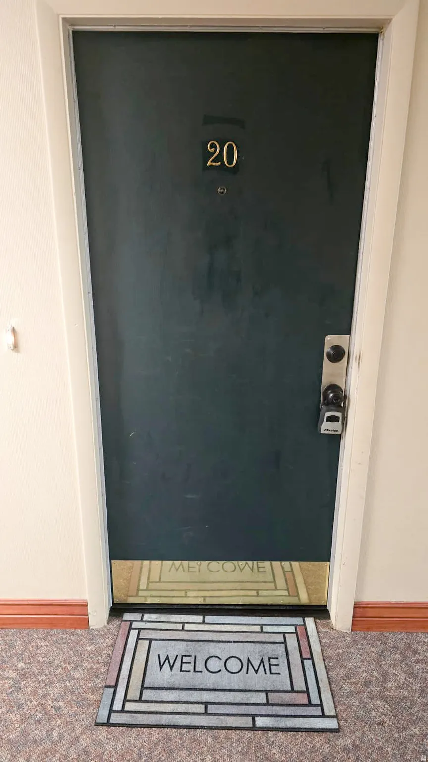 Dark-finish entry door with brass-tone numbering and a contemporary door handle with a deadbolt