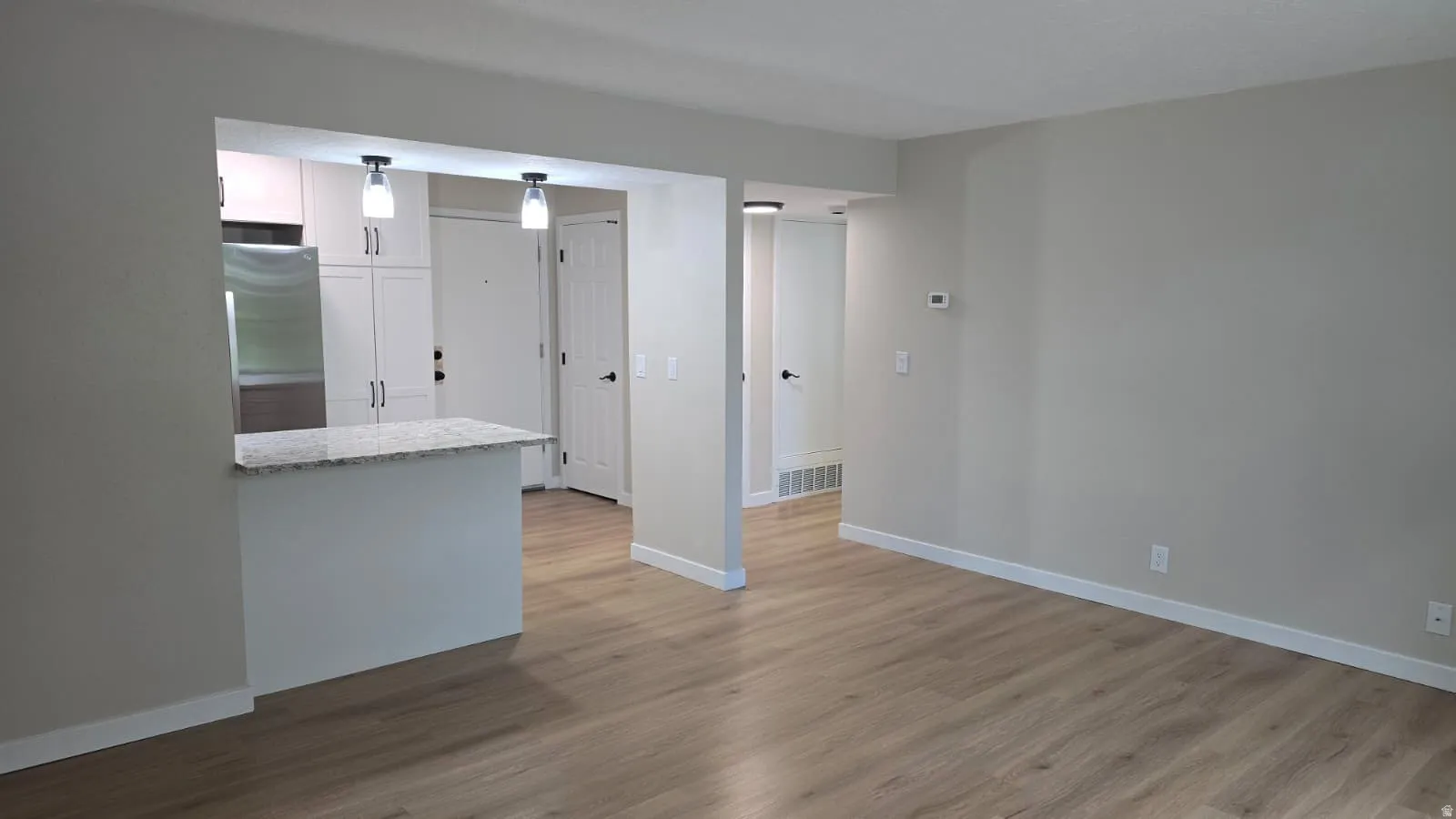 Open concept living area featuring wood-finish flooring and light-toned wall paint