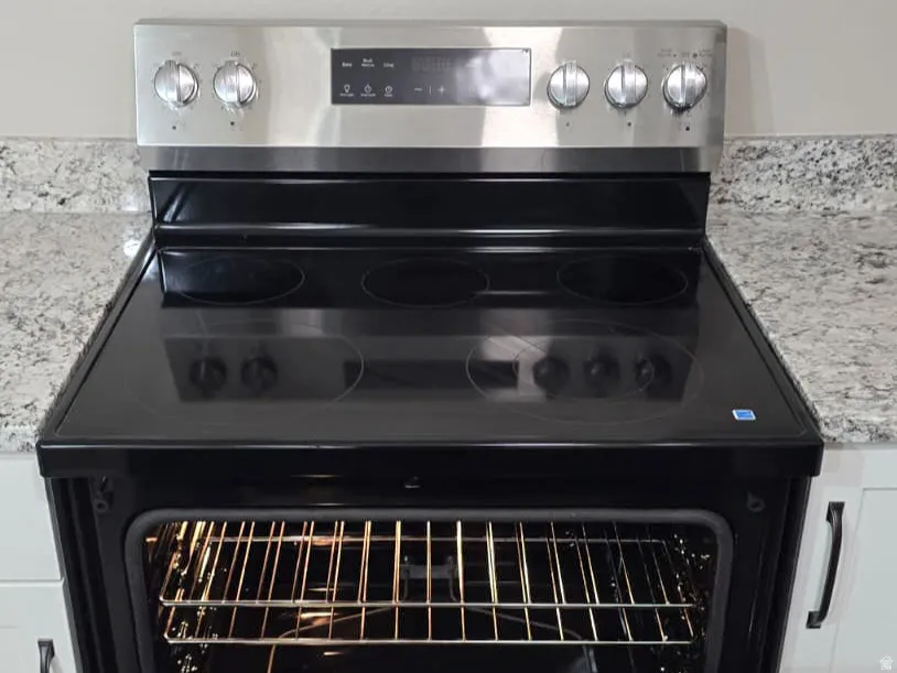 Stainless steel electric range with a black glass cooktop and an integrated lower storage drawer