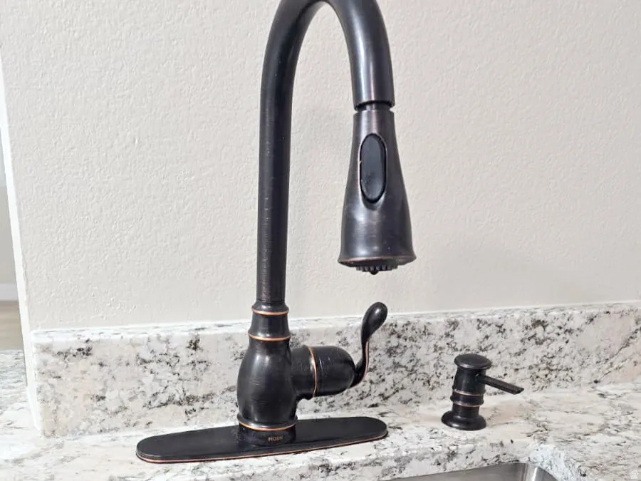 Stainless steel undermount sink with a garbage disposal and a gooseneck faucet in an oil-rubbed bronze finish