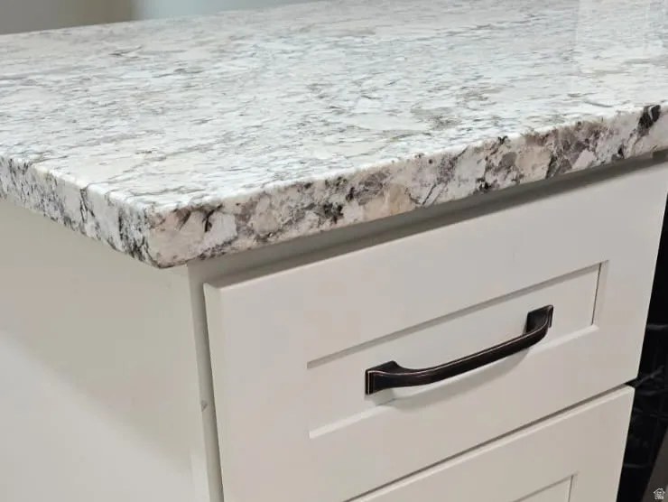White shaker-style cabinetry featuring black hardware, a light-toned countertop, and wood-finish flooring