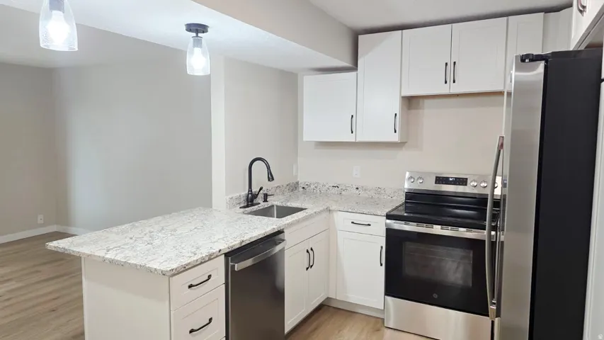Kitchen featuring white cabinetry, light-toned countertops, a stainless steel dishwasher, a stainless steel range, and a stainless steel refrigerator