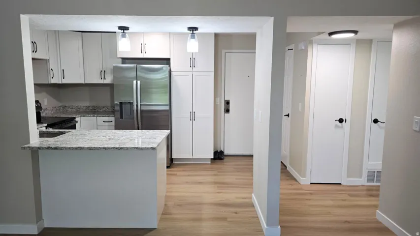 Renovated kitchen featuring light cabinetry, stainless steel appliances, and a granite-finish countertop island