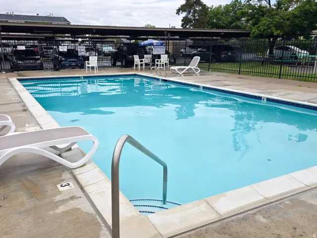 Rectangular in-ground swimming pool with light blue water and concrete decking